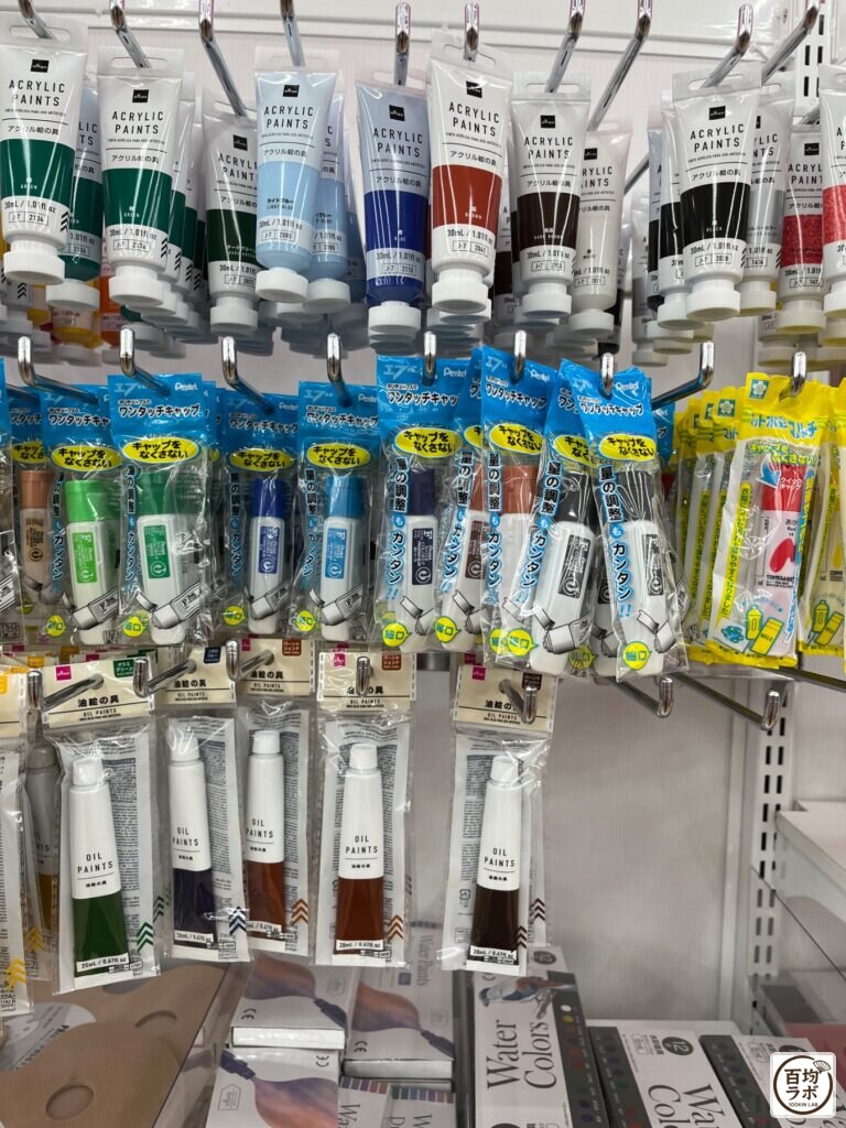 ダイソー 東戸塚の電池・電気小物売り場に並ぶアクリル絵の具、ワンタッチキャップ（絵の具用）など計3商品（2026年8月11日撮影）
