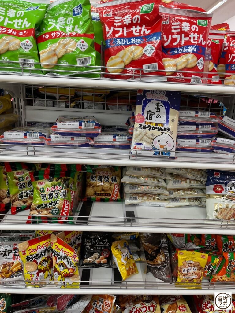 ダイソー 東戸塚の食品・飲料売り場に並ぶ三幸のソフトせん（サラダ味・えびしお味）、雪の宿 ミルクかりんとうなど計9商品（2026年8月12日撮影）