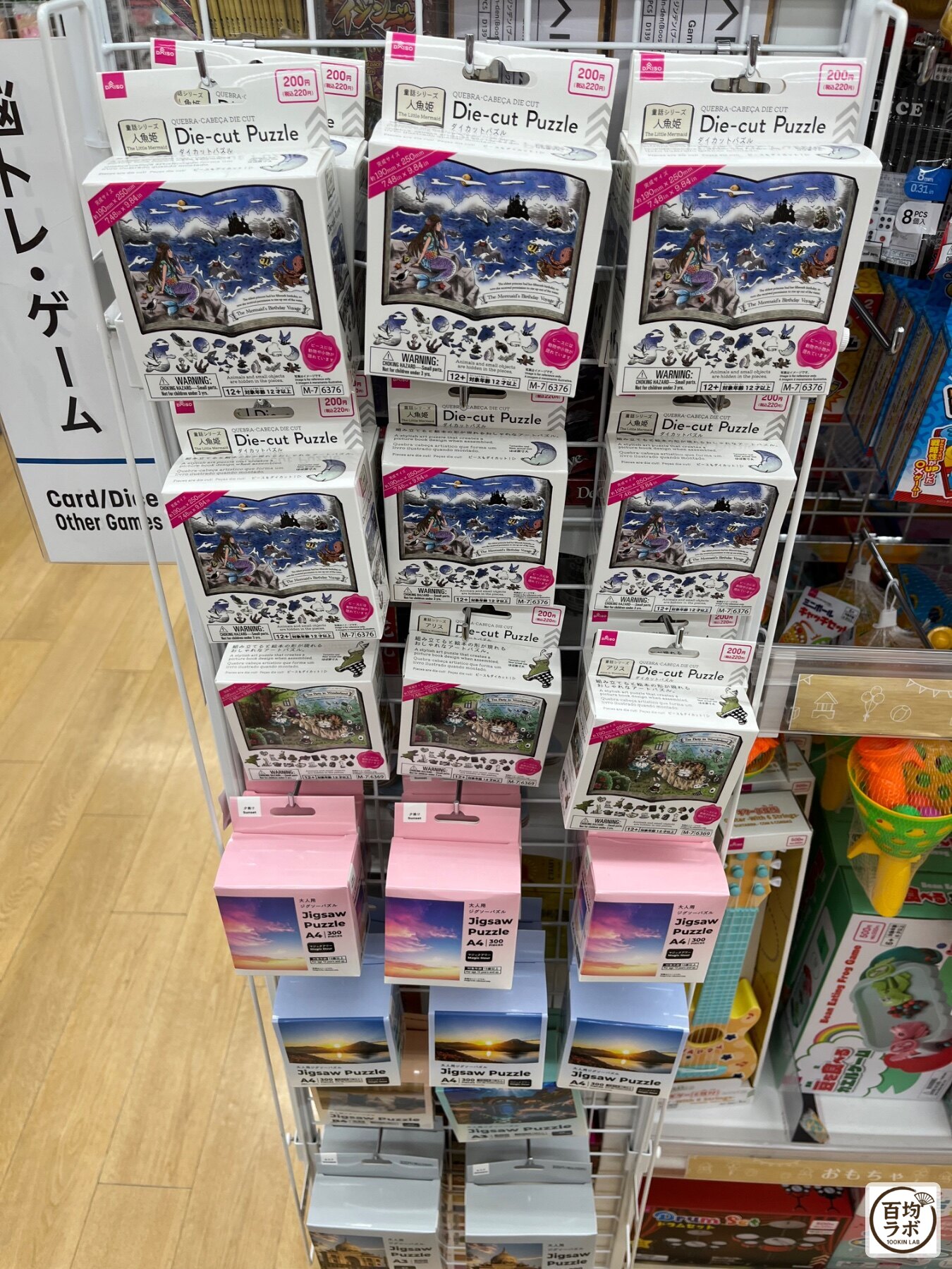 ダイソー 東戸塚のおもちゃ売り場に並ぶダイカットパズル（人魚姫）、ダイカットパズル（不思議の国のアリス）など計3商品（2026年8月12日撮影）