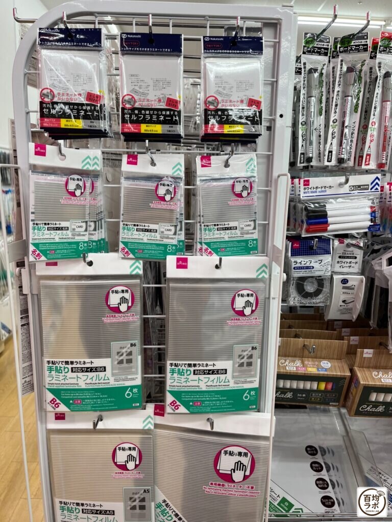 ダイソー 東戸塚の文房具売り場に並ぶセルフラミネート（トレカサイズ）、手貼りラミネートフィルム（カードサイズ）など計9商品（2026年8月13日撮影）