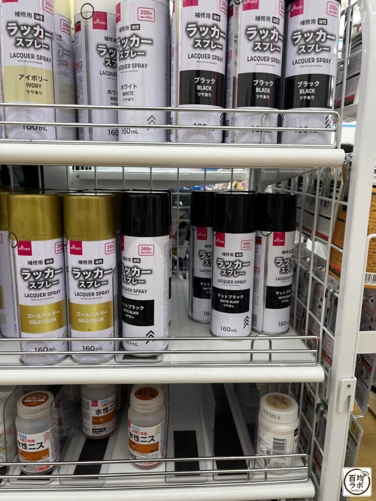 ダイソー 東戸塚のDIY・工具売り場に並ぶ補修用 油性ラッカースプレー(アイボリー・ホワイト・ブラック・ゴールド・マットブラック)、水性ニスなど計3商品(2026年8月14日撮影)